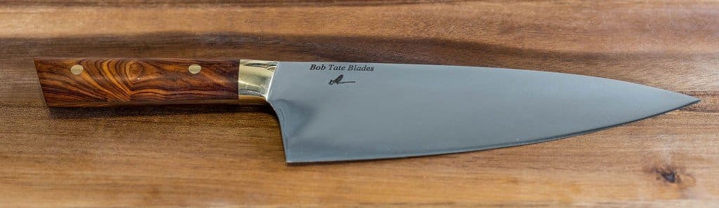 A knife with the blade cut off on top of a wooden table.