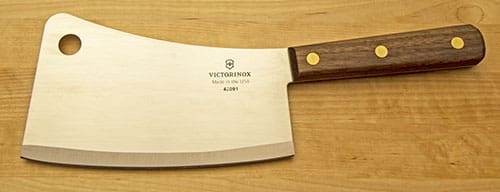 A large wooden handled cleaver knife on top of a table.