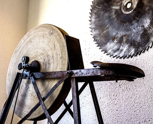 A large metal wheel sitting on top of an old wooden stand.