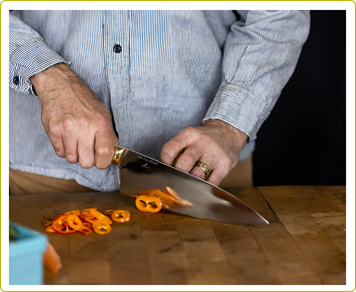 A person slicing orange peels on top of a wooden table.